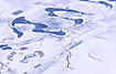 Snowcovered landscape with a meandering iced river and a straigt road/water channel