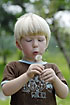 Boy blows dandelion seeds up in the air