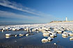 Ice formations at the sea shore with lighthouse in the background