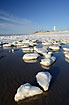 Ice formations at the sea shore with lighthouse in the background
