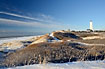 The white light house stands among snow covered dunes this winters morning