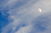 Feather-like clouds and half moon on the blue sky