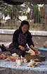 A lao woman in the process of chopping a chicken 