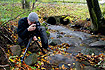 Naturephotographer trying to capture the autumn athmosphere by a forest stream