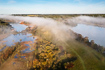 Beautiful misty morning in varied landcape with forest, grassland, lakes and bogs. Drone photo
