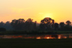 Sunset over a pond with an empty bench in the foreground