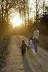 Mother and child walking towards the sun in the forest